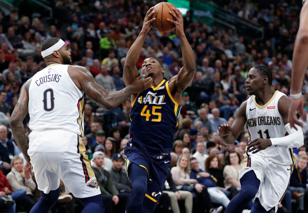 Jan 3, 2018; Salt Lake City, UT, USA; Utah Jazz guard Donovan Mitchell (45) drives to the hoop against New Orleans Pelicans center DeMarcus Cousins (0) and guard Jrue Holiday (11) in the fourth quarter at Vivint Smart Home Arena. Mandatory Credit: Jeff Swinger-USA TODAY Sports